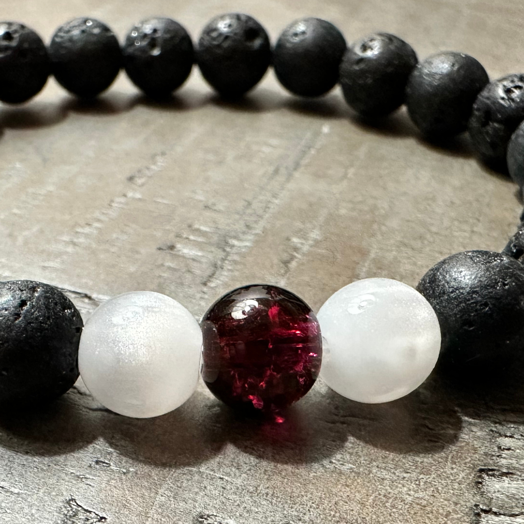 Redemption Christian Bracelet with black lava stone beads, frosted white beads, and a deep red centerpiece bead – faith jewelry by Salt and Light Merch.