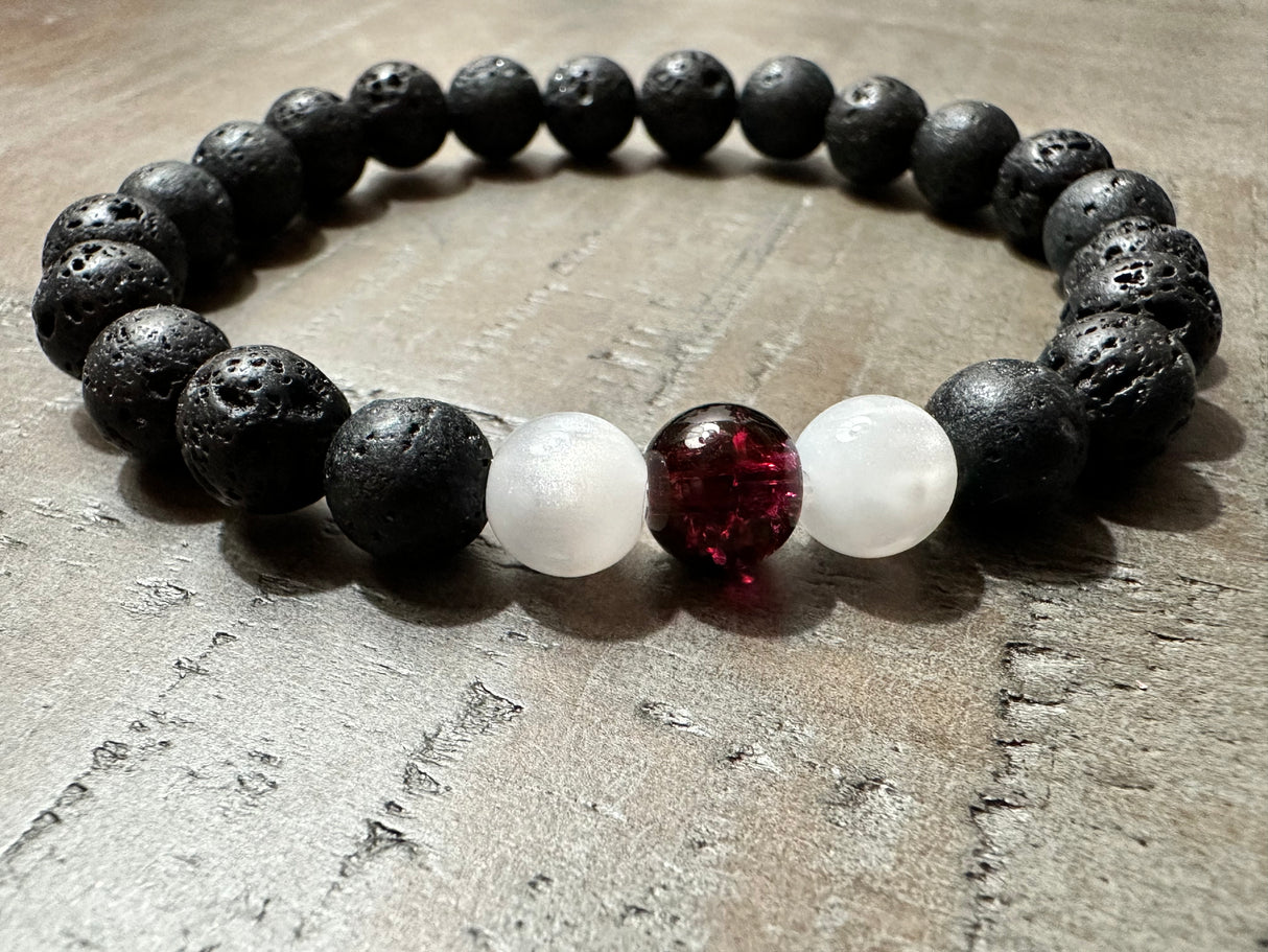 Redemption Christian Bracelet with black lava stone beads, frosted white beads, and a deep red centerpiece bead – faith jewelry by Salt and Light Merch.