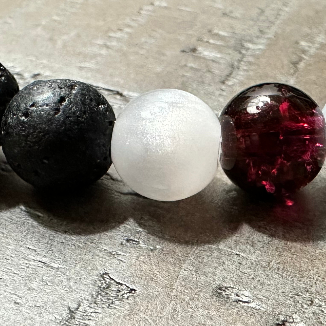 Close-up of Redemption Bracelet showing black lava stone beads, frosted white glass beads, and a red accent bead symbolizing the blood of Jesus. Salt and Light