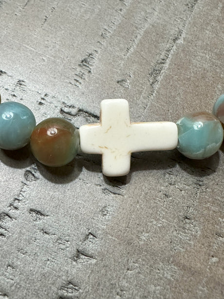 Salt and Light Merch Christian bracelet – polished gemstone beads in soft blush and champagne tones with a rhinestone cross charm. Shown in a close-up product photo for Christian faith jewelry.