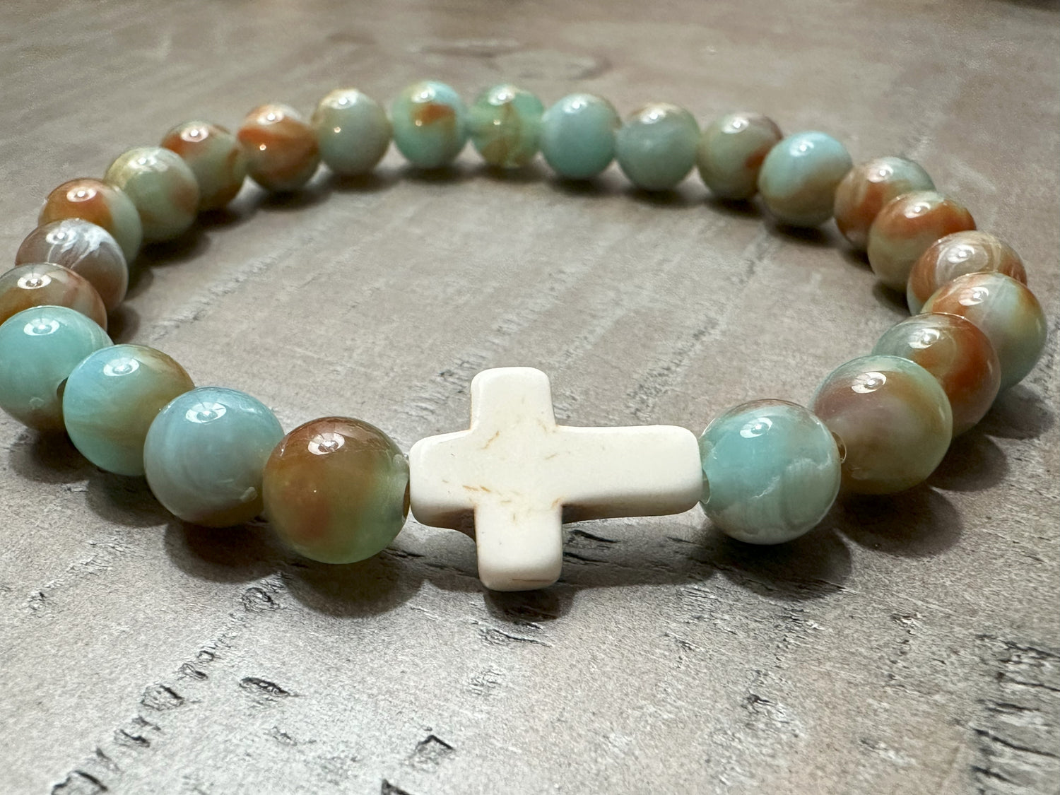 salt and Light Merch Christian bracelet – polished gemstone beads in soft blush and champagne tones with a rhinestone cross charm. Shown in a close-up product photo for Christian faith jewelry.”
