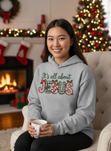 Salt and Light Merch Christmas Hoodie Person wearing a hoodie with 'It's all about Jesus' text in a festive room with Christmas decorations.
