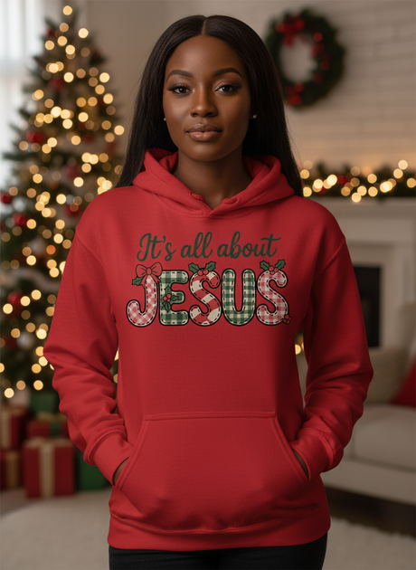 Salt and Light Merch Christmas Hoodie Person wearing a red hoodie with 'It's all about Jesus' text in a decorated room.